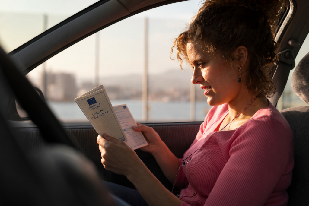 Donna legge la carta di circolazione in auto