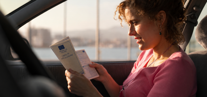 Donna legge la carta di circolazione in auto